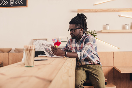 african american man reading business newspaper while sitting at bar counter の写真素材