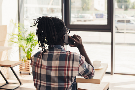 rear view of african american man talking on smartphone in cafeの写真素材