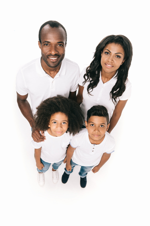 high angle view of happy african american family with two kids smiling at camera isolated on whiteの写真素材