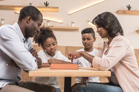 adorable african-american family using tablet in cafeの写真素材