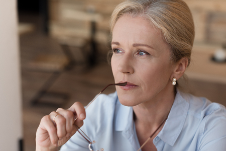 portrait of beautiful mature woman with eyeglasses and looking awayの写真素材