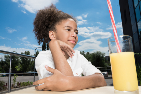 beautiful afro girl with orange juice in cafeの写真素材