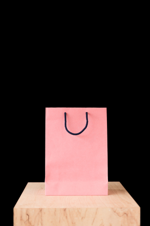 pink shopping bag on wooden tabletop isolated on blackの写真素材
