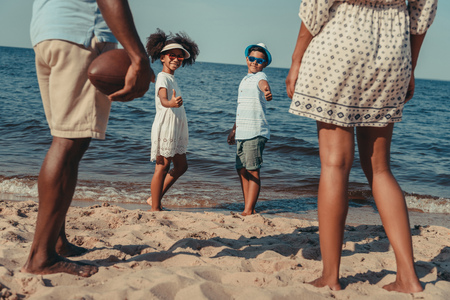 cropped shot of african american family playing with rugby ball on beach の写真素材