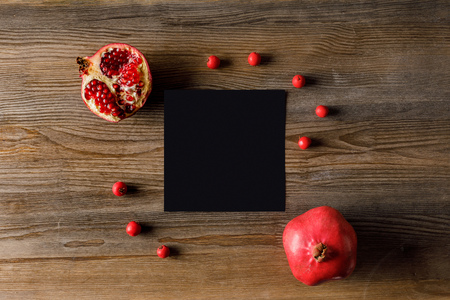 top view of black empty card with pomegranates on wooden tabletopの写真素材