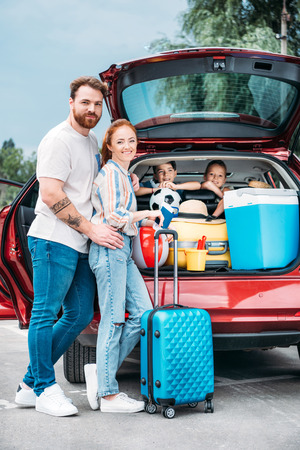 happy young family packing luggage in car trunkの写真素材