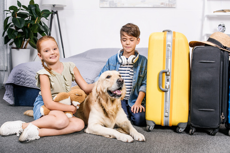 adorable kids  in bedroom with dog and yellow suitcase for tripの写真素材
