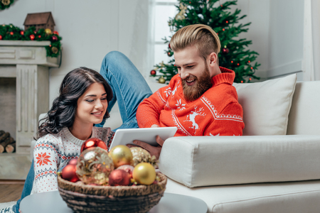 happy couple using tablet in christmas decorated roomの写真素材