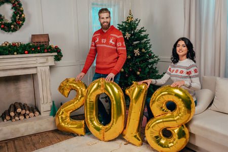 beautiful young couple with new year balloons in shape of numbers