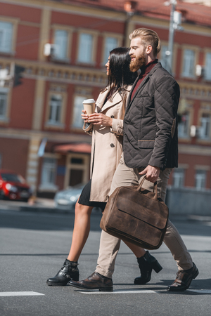 fashionable couple walking outdoors with disposable cup of coffeeの写真素材