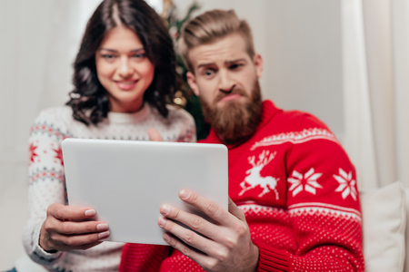 cute couple using tablet in christmas decorated roomの写真素材
