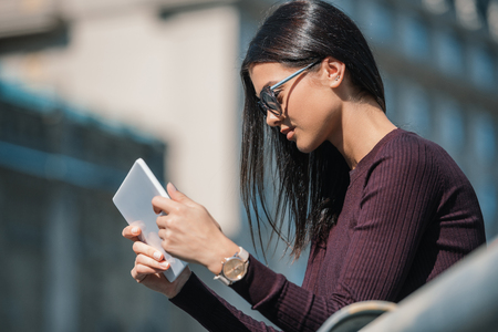 young happy woman using tablet outdoors on sunny dayの写真素材
