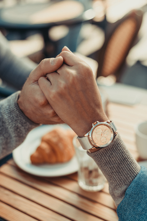 cropped shot of young couple holding hands in cafeの写真素材