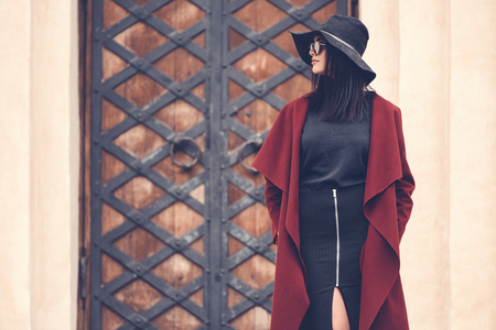 fashionable young woman in stylish clothing posing next to old building doorsの写真素材