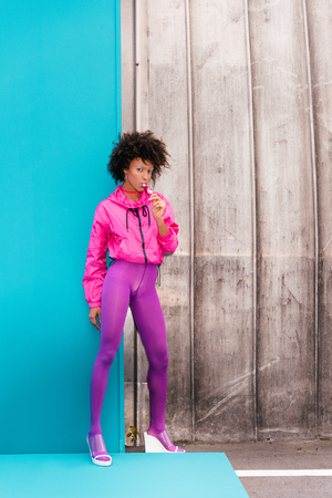 fashionable afro girl with popsicle posing in 80s style clothes on turquoise の写真素材