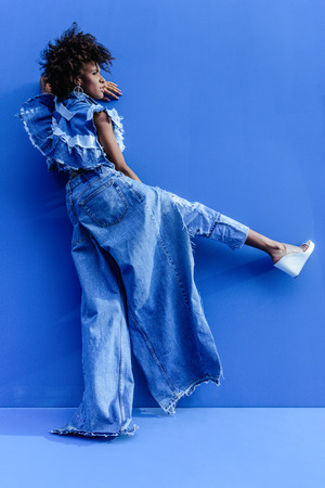 afro girl in denim clothes posing for fashion shoot on blueの写真素材