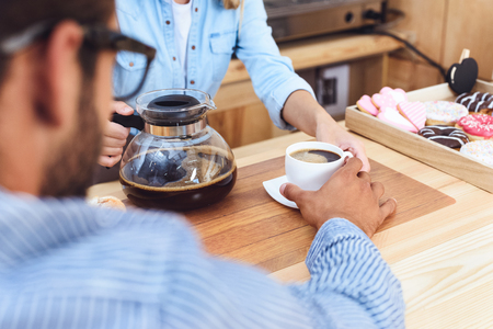 cropped shot of waitress pouring coffee to client in cafeの写真素材