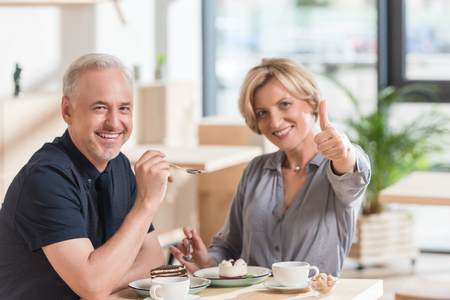 Woman showing thumb up for sweets at cafeの写真素材