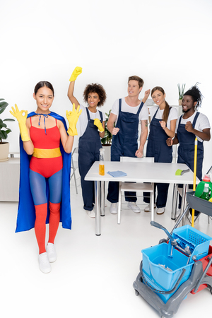 happy multiethnic group of professional cleaners working together while girl in superhero costume showing ok sign の写真素材
