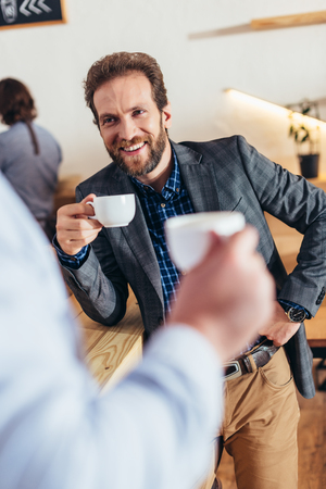 cropped shot of businessmen holding cups of coffee and looking at each otherの写真素材