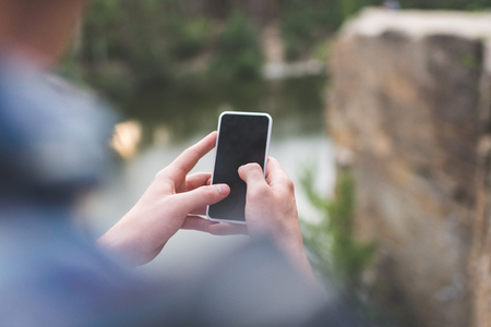 cropped shot of man using smartphone outdoors on natureの写真素材