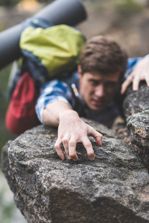close-up shot of young hiker climbing on rockの写真素材