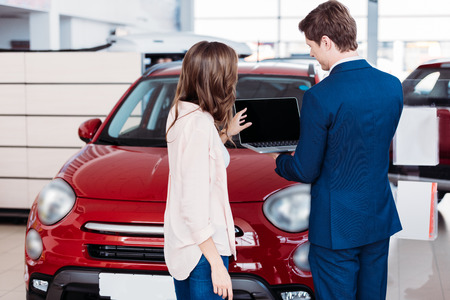 manager showing something on a laptop to the customer in car showroomの写真素材