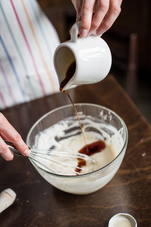 partial view of woman pouring honey into bowl with creamの写真素材