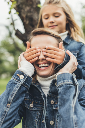 daughter making surprise and closing eyes to her smiling mother  の写真素材