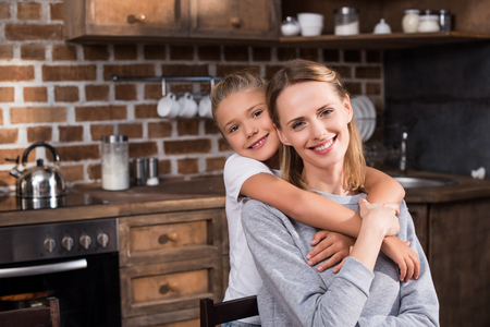 portrait of little daughter hugging happy mother at homeの写真素材