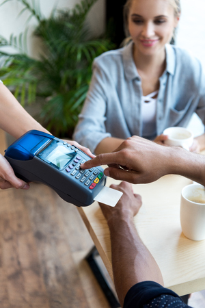 cropped shot of man paying by credit card and terminal in cafeの写真素材