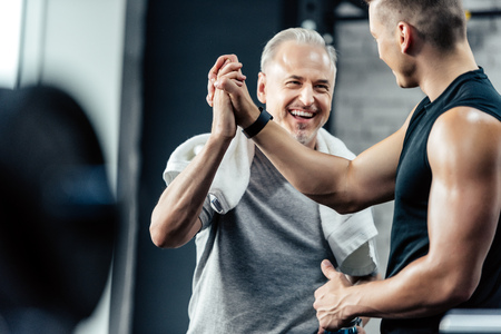 senior sportsman giving highfive to trainer in sport centerの写真素材