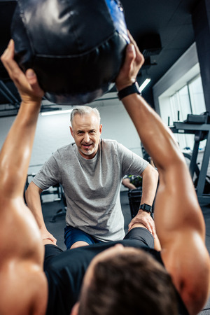 young sportsman training with medicine ball in gym with senior trainer の写真素材