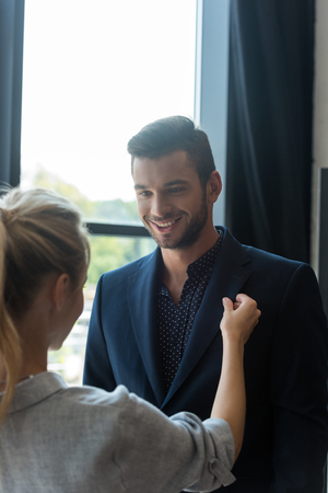 cropped shot of young woman looking at boyfriend trying on suit in boutiqueの写真素材