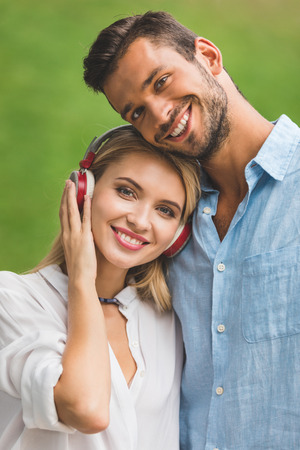 portrait of smiling woman in headphones and boyfriend looking at cameraの写真素材
