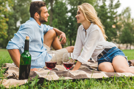 selective focus of bottle and glasses of red wine with couple on romantic date behindの写真素材