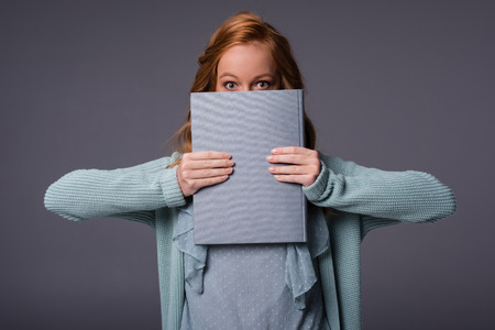 beautiful girl in blue clothes holding book, isolated on grey 