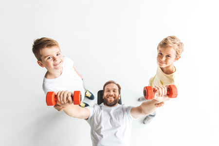 top view of father and sons exercising with dumbbells and smiling at cameraの写真素材