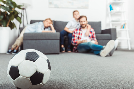 close-up view of soccer ball and father with sons sitting behindの写真素材