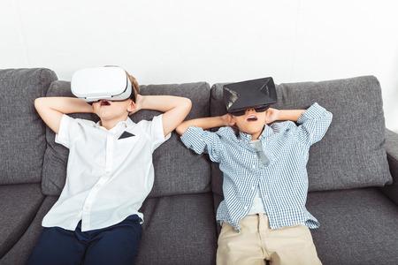 shocked little boys using virtual reality headsets at homeの写真素材