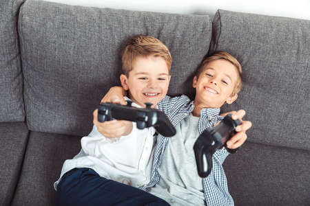 happy little brothers holding gamepads and smiling at camera の写真素材