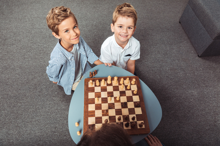 high angle view of little boys playing chess and smiling at cameraの写真素材