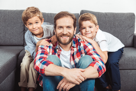 portrait of happy father with sons smiling at cameraの写真素材