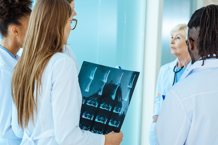 A multiracial group of medical interns with x-ray photograph listening to elder doctor