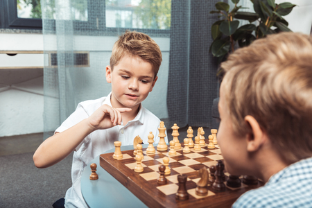 cute focused little boys playing chess together at homeの写真素材