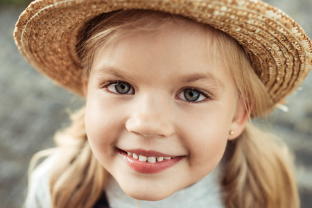 portrait of smiling little girl in straw hat looking at cameraの写真素材