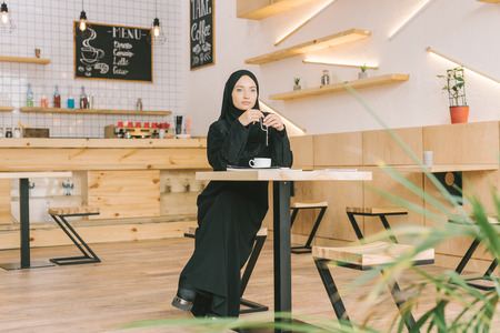 beautiful muslim woman with prayer beads sitting in cafeの写真素材
