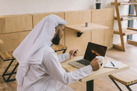 concentrated muslim man in cafe looking at laptopの写真素材