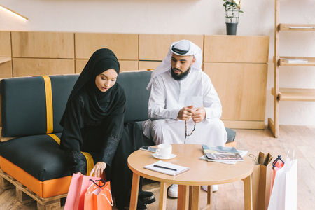 beautiful muslim couple sitting on couch after shopping