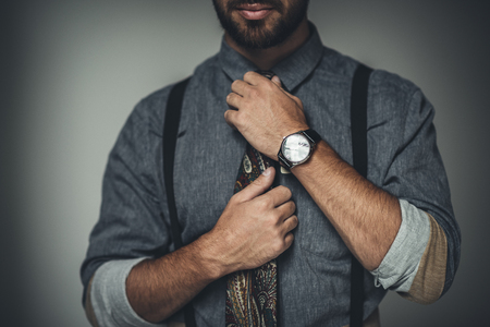 Cropped shot of young bearded man adjusting his tieの写真素材